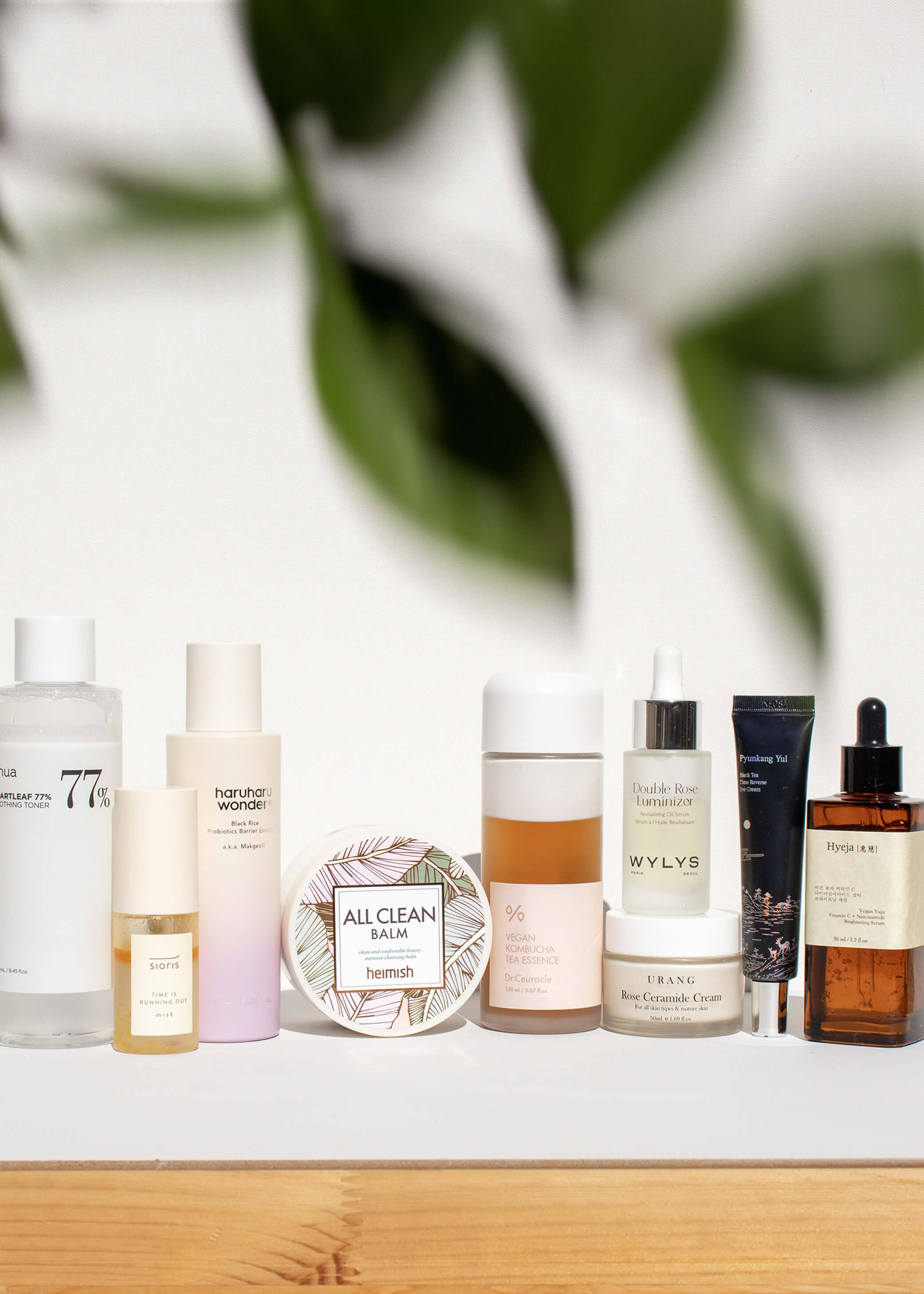Collection of skincare and hair care products on a wooden surface with a blurred green leafy background.