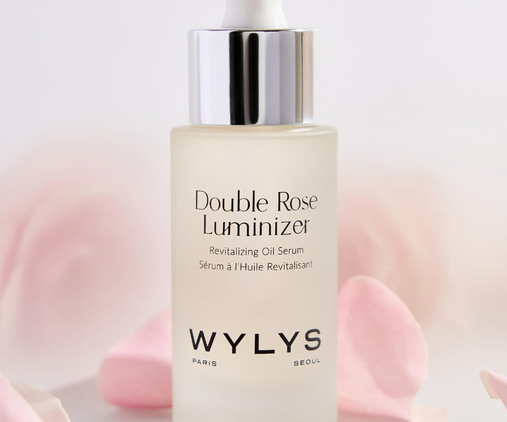 Wylys Double Rose Luminizer serum bottle with pink petals on a light background