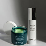 WYLYS Phyto Green Cleansing Balm and New Day Glow Brightening Pressed Serum on a white surface with shadows.
