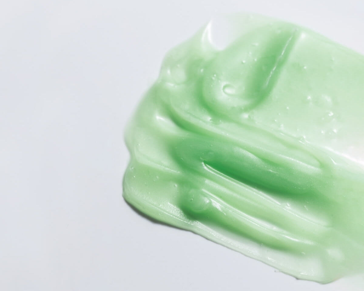 Texture shot of WYLYS Phyto Green Cleansing Balm showing its semi-transparent green gel-to-oil consistency.
