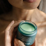 A person holding an open jar of WYLYS Phyto Green Cleansing Balm, highlighting the plant-powered green formula