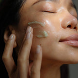 Close-up of a woman applying WYLYS Phyto Green Cleansing Balm to her cheek for a glowing complexion.