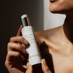 A woman holding the WYLYS New Day Glow Vitamin C + Bakuchiol Brightening Pressed Serum pump bottle.