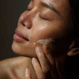 Close-up of a woman applying the creamy WYLYS New Day Glow serum to her face for skin brightening.