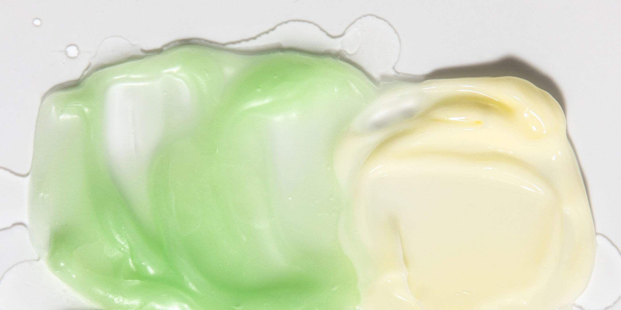 Texture on white background of two products: Green Cleansing Balm and Light yellow Cream Serum