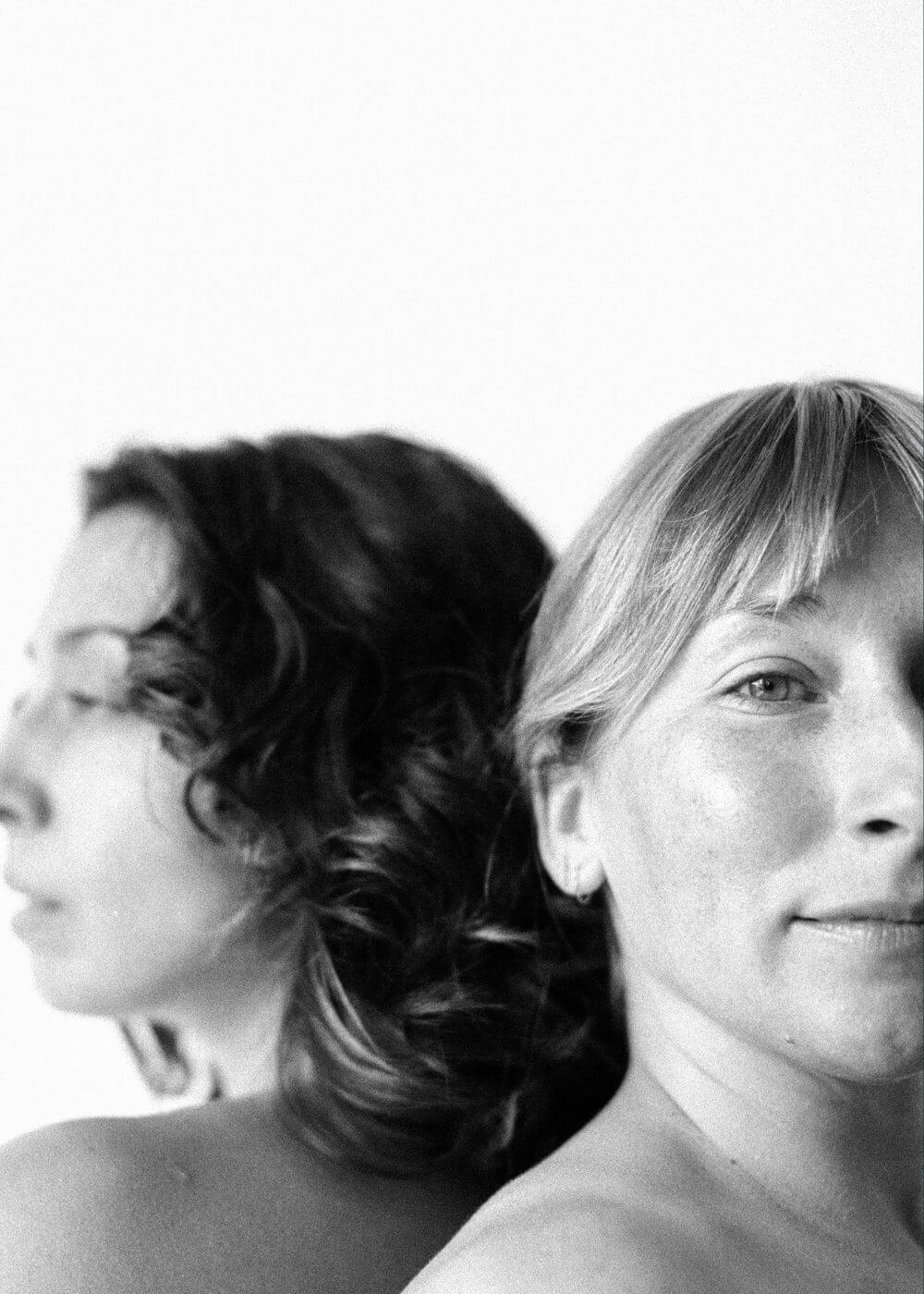 Black and white photo of two women, one with a blurred face and the other smiling.